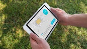 Two hands holding an iPad with the SWAY assessment application instructions displayed on the screen.