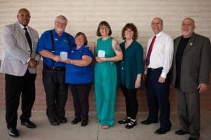 Award winners holding their awards and posing with community leaders. Pictured (left to right): Wayne Bell, District Director of Wichita Office of the U.S. Small Business Administration; Mark Buckley, Owner of Toy Depot, Inc.; Geneva Nisly, Owner of Toy Depot, Inc.; Sarah Leslie, Owner of Leslie Coffee Co.; Mary Ware, Kansas State Senator; Tom Sawyer, Kansas State Representative; Frank Choriego, Associate Director of Kansas SBDC at Wichita State University.