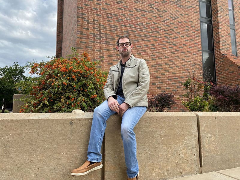 Photo of JW Webster, certified Cherokee language instructor at Wichita State, outside of Lindquist Hall.