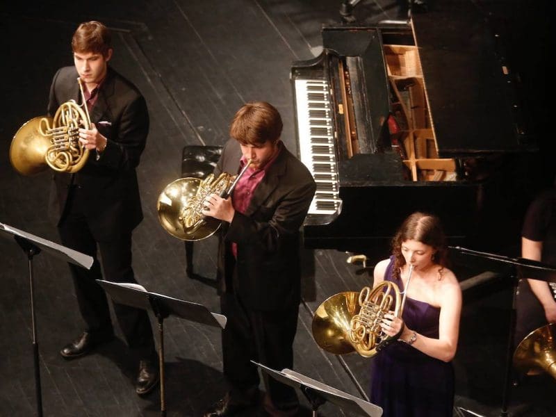 Picture of three Wichita State students playing the French Horn.