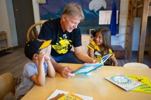 Picture of Rick Case reading to two children as part of Wu Crew Reads.