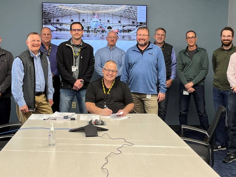 Members of Boeing pose around conference table.