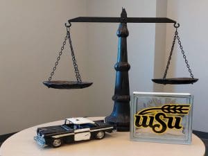 Picture of scales, miniature police car and WSU plaque on desk.