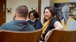 Three adult learners laugh and talk at a gathering.