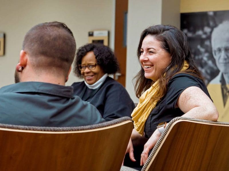 Three adult learners laugh and talk at a gathering.