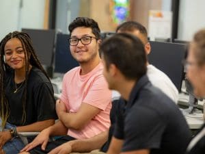 Image of five students chatting on couch.