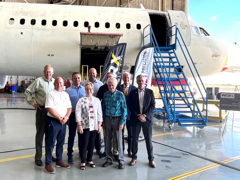 Image of nine member outside aircraft posing for photo at NIAR.