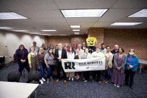 Image of Wu and President Rick Muma posing with University Libraries staff holding a banner.