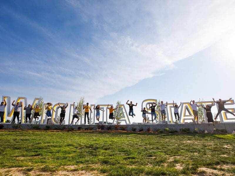 Image of Wichita State sign with student jumping in front of it.