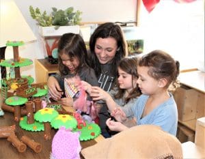 A photo of a pre-kindergarten teacher with students