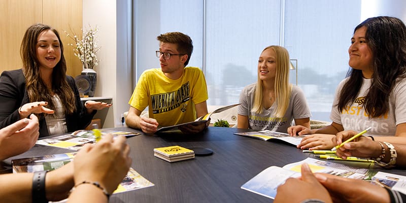 Photo of an office worker assisting students.