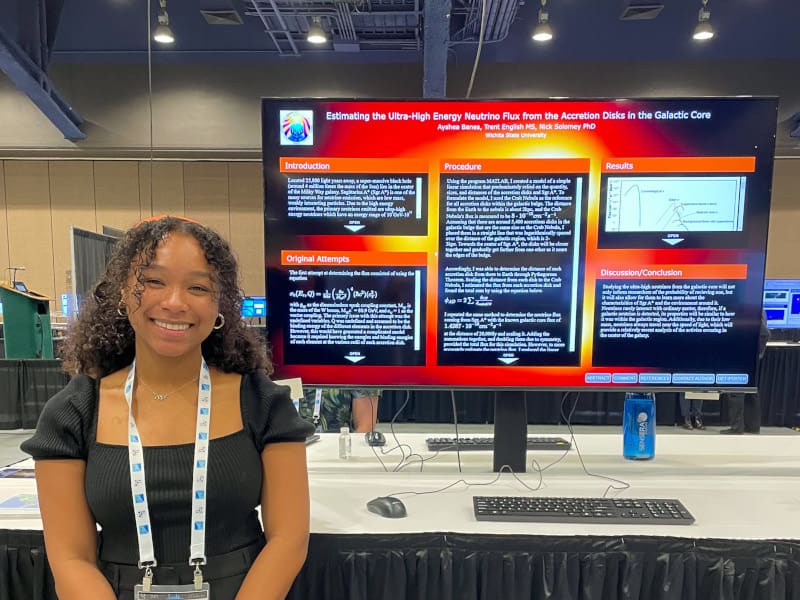 Photo of Ayshea Banes in front of her presentation poster.