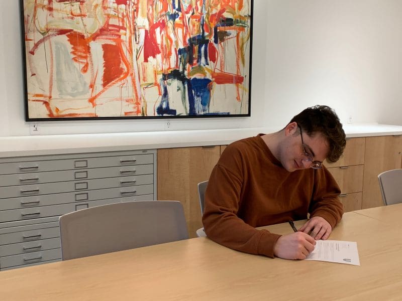 A photo of a student filling out their scholarship form in the Ulrich Collection Study Center.