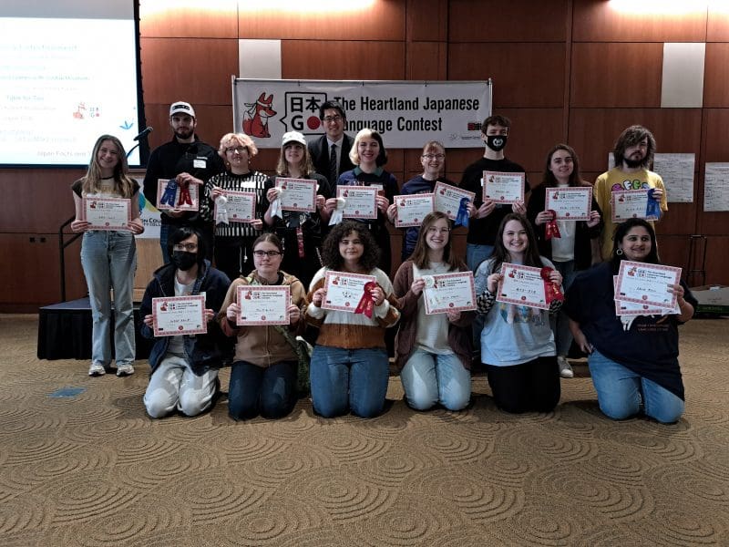 Photo of the contest winners in two rows holding the certificates and ribbons they received as prizes.