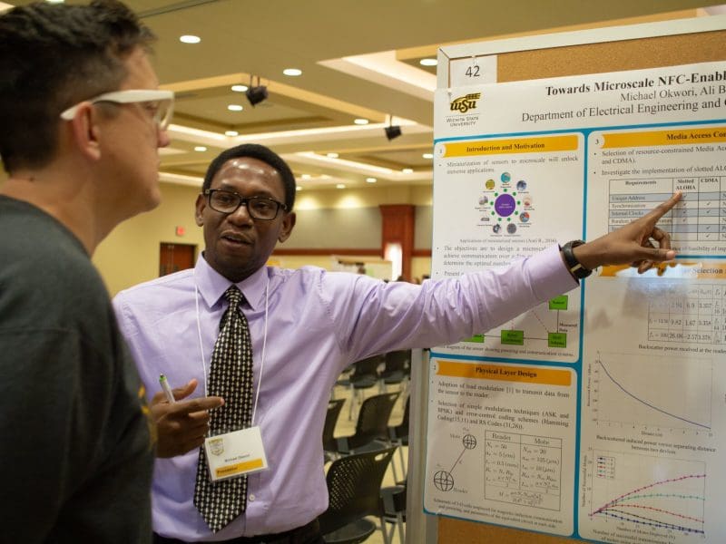 Photo of a student presenting his research poster in the GRASP Symposium at Wichita State.