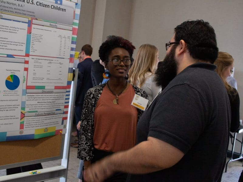 Photo of two students talking about a research poster in GRASP.