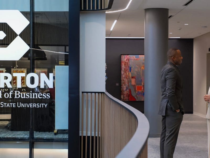 Woman CEO speaks with male grad student in Woolsey Hall, home of the Barton School of Business.