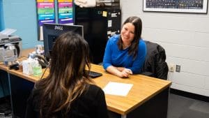 An academic advisor sits at a desk facing a student.