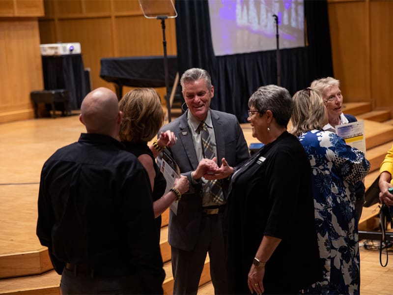 President Rick Muma speaks with the other speakers at the 2023 Fall Address