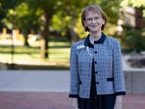 Kathy Downes stands in the courtyard in front of the Ablah Library