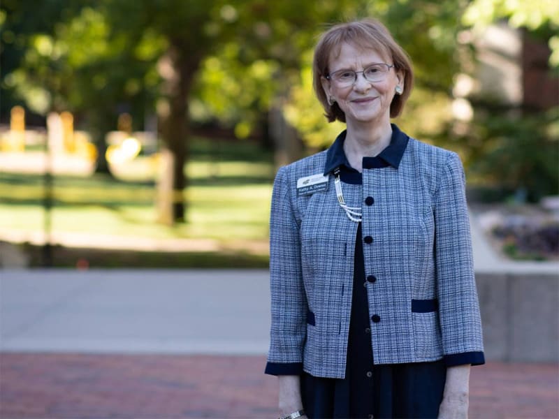 Kathy Downes stands in the courtyard in front of the Ablah Library