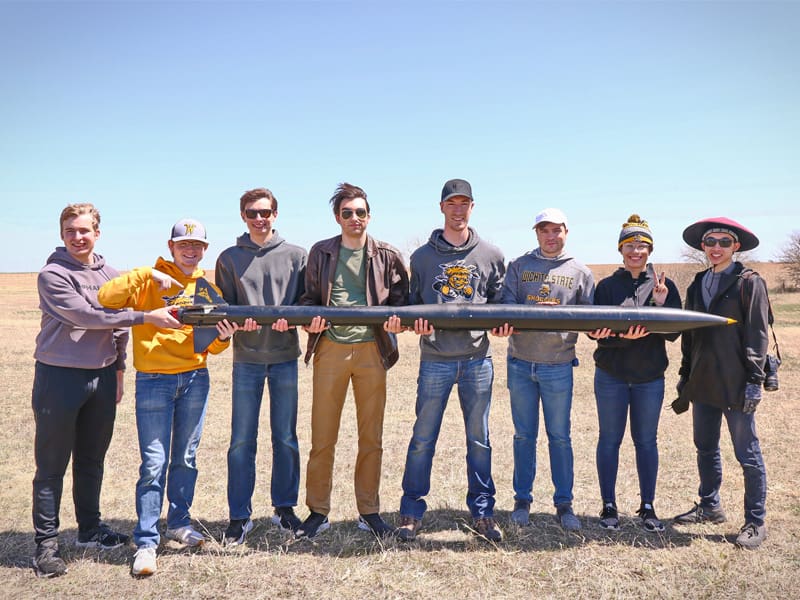 Members of the WSU Rocket Club pose with one of their rockets