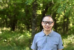 Hong Tien Vu stands in front of a wooded area