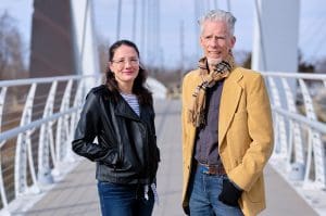 A man and a woman are standing together on a bridge