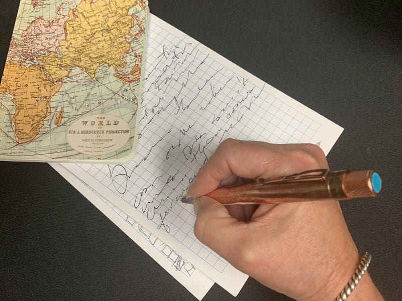 A hand is writing on a note pad.