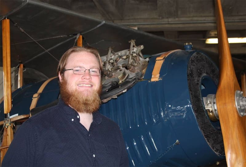 Kian Williams stands in front of a plane at the Kansas Aviation Museum