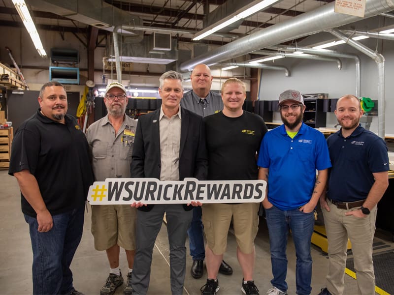 President Rick Muma holds a Rick Rewards sign with staff from Building Trades