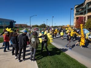 Shocktoberfest parade marches with participants handing out items to spectators