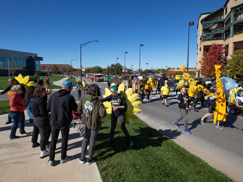 Shocktoberfest parade marches with participants handing out items to spectators