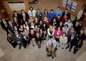 A group of 40 student researchers standing in the capitol building rotunda and looking up at the photographer