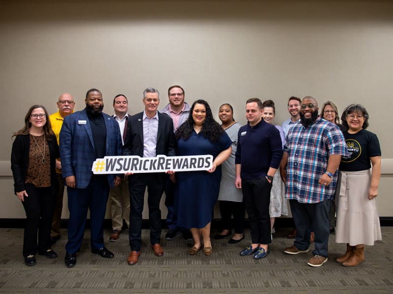 Members of the WSU CARE Team pose with President Rick Muma holding a sign saying "Rick Rewards"