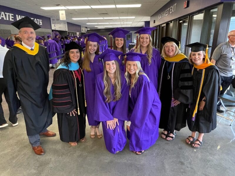 A photo of 9 people in graduation robes.