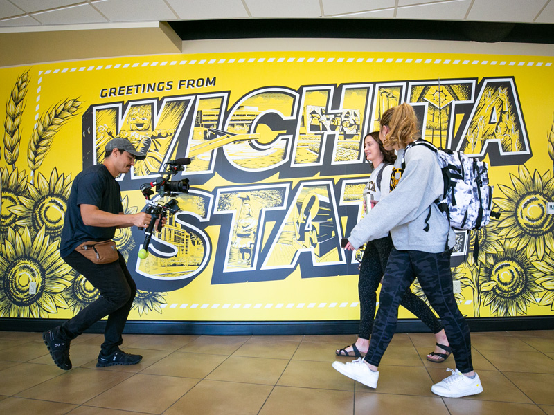 Students in the middle of filming in front of the Wichita State mural in the RSC.