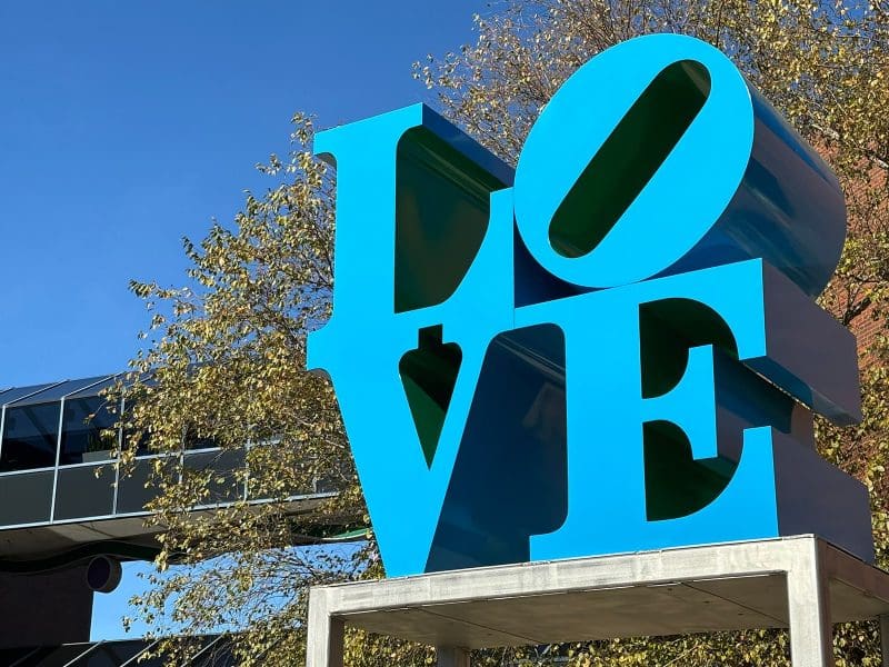 A close-up image of Robert Indiana's sculpture LOVE, a large rendering of the word "Love" in blue and green metal.