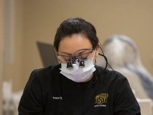 Dental hygienist looking down while wearing dental loupes
