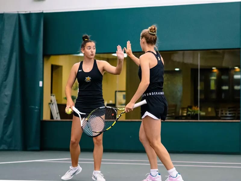 Women's tennis players celebrate after a successful set
