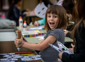 A happy girl enjoys making an art project.