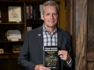 President Richard Muma poses with his book "Student Centered, Innovation Driven."