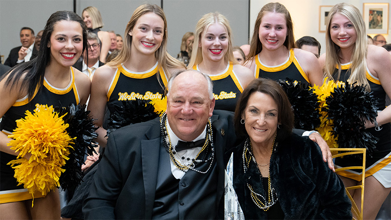 Steve and Regine Feilmeier pose with Wichita State Cheerleaders