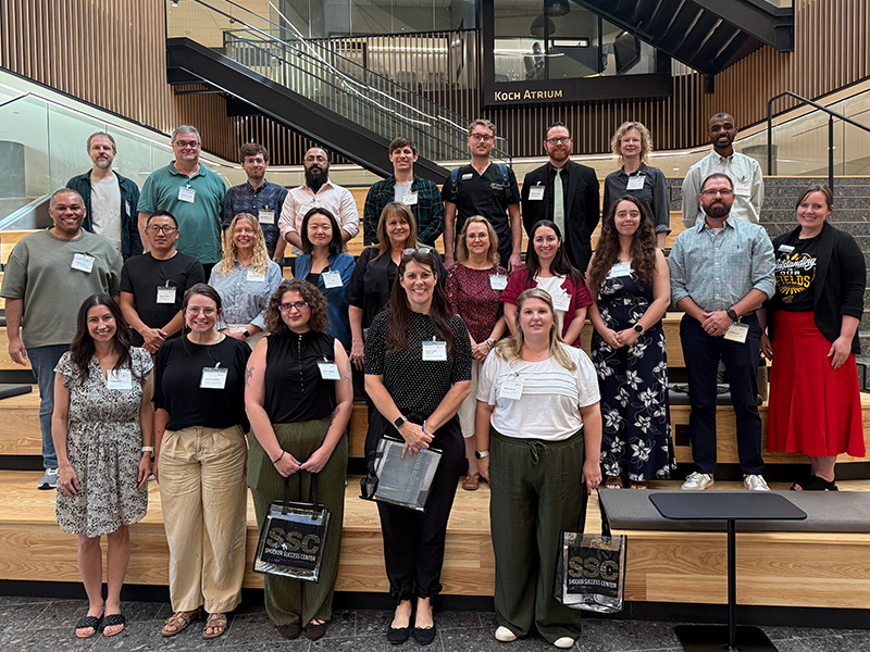 Faculty post in front of a set of stares. Each person is wearing a name tag.