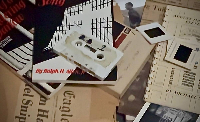 A still from the documentary showing various documents, books, tapes and photos.